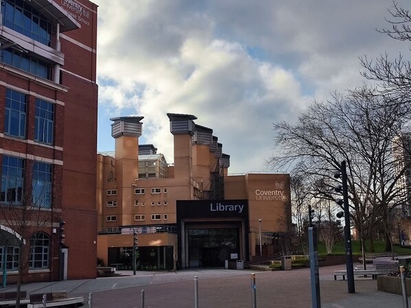 A building with a prominent 'Coventry University Library' sign, a brick facade, and a modern design with multiple chimneys. - Bright & Cosy Studio in Central Coventry (Coventry)