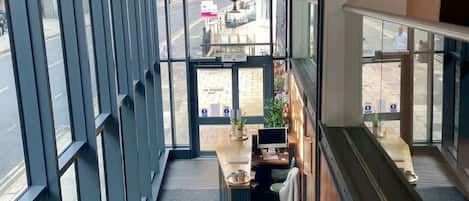 A modern interior with a staircase, a seating area with a counter, and large windows.