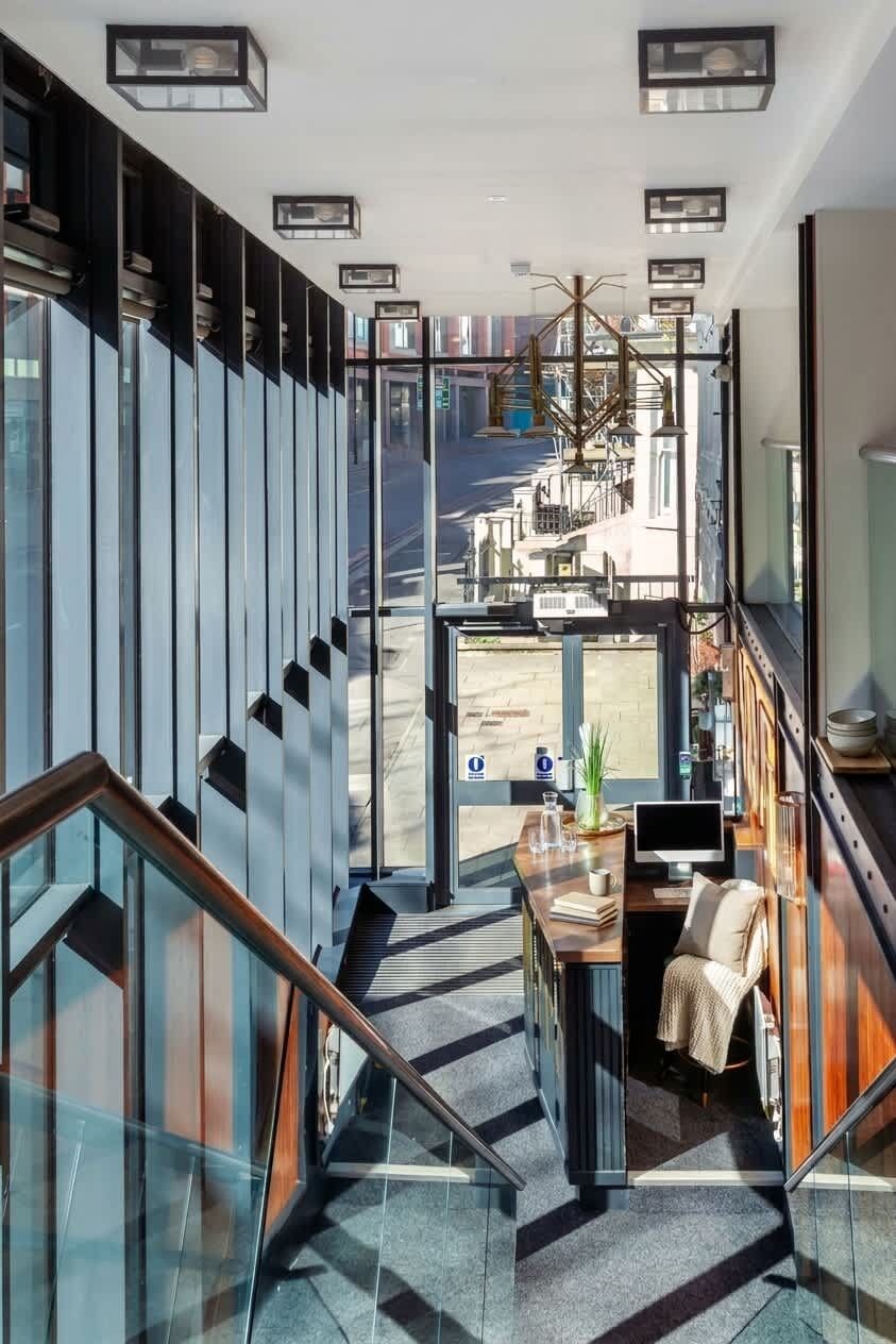 Ein modernes Interieur mit einer Glastreppe, einem Schreibtisch mit Computer und Blick ins Freie.