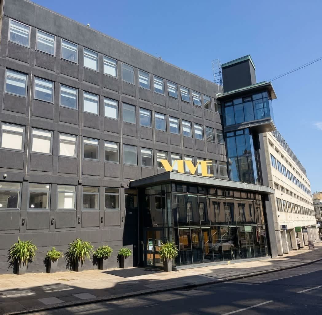 Un edificio moderno con un evidente cartello 'VIVE', ampie finestre e un ingresso in vetro.