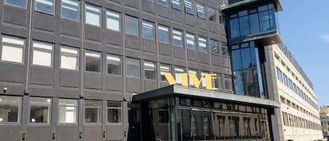 Un edificio moderno con un llamativo letrero 'VIVE', amplias ventanas y una entrada de vidrio.