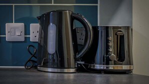 A kitchen with a kettle and a coffee maker on the counter, a power outlet, and a switch. - Budget Double Studio Room in Central Nottingham (Nottingham)