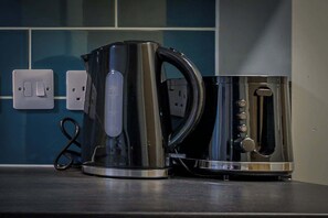 A kitchen with a kettle and a coffee maker on the counter, a power outlet, and a switch. - Budget Double Studio Room in Central Nottingham (Nottingham)