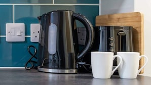 A kitchen area with a black electric kettle, two white mugs, and a wooden cutting board. - Cosy Budget Double Studio in Nottingham Centre (Nottingham)