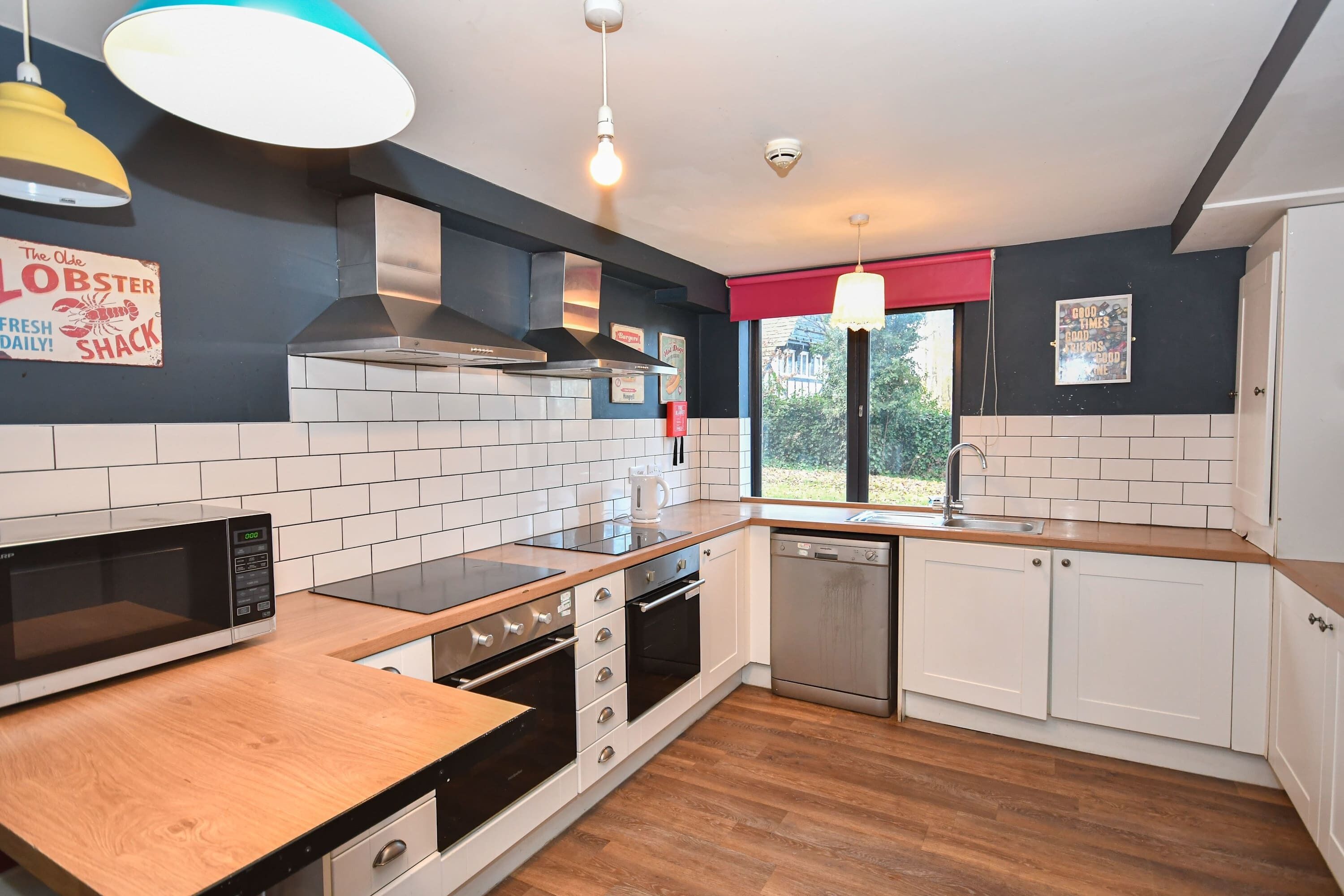 A modern kitchen with white cabinets, a stainless steel dishwasher, a microwave, and a wooden countertop.