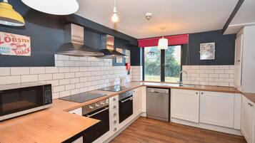 A modern kitchen with white cabinets, a stainless steel dishwasher, a microwave, and a wooden countertop.