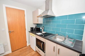 A compact kitchen with a microwave, oven, sink, and a teal backsplash. - Convenient Budget Studio in Central Sheffield (Sheffield)
