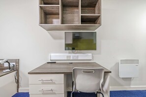 A room with a desk, chair, shelf, and wall-mounted air conditioner. - Modern Budget Single Studio in Central Nottingham (Nottingham)