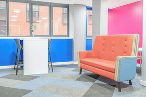 A room with a checkered carpet, a red armchair, a white desk, and a window with a view of a brick building. - Modern Budget Single Studio in Central Nottingham (Nottingham)