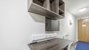 A room with a desk, chair, mounted TV, and a door with a sign. - Modern Budget Single Studio in Central Nottingham (Nottingham)