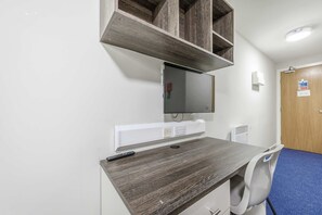 A room with a desk, chair, mounted TV, and a door with a sign. - Modern Budget Single Studio in Central Nottingham (Nottingham)