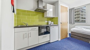 A compact kitchen with white cabinets, a microwave, and a built-in oven. - Modern Budget Single Studio in Central Nottingham (Nottingham)