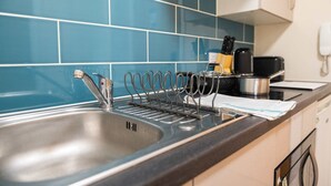 A kitchen with a stainless steel sink, a dish rack, and a coffee maker. - Cosy Budget Single Studio in Central Nottingham (Nottingham)