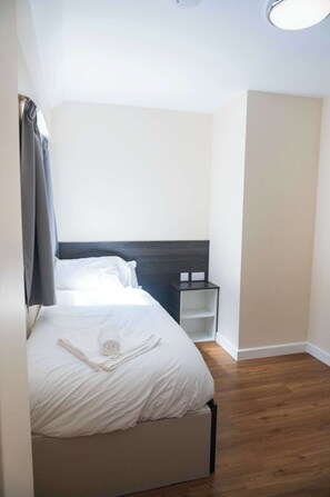 Ein Schlafzimmer mit einem Bett, einem Nachttisch und Holzboden.