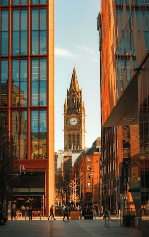 A cityscape with modern buildings, a historic clock tower, and pedestrians. - Contemporary 2 Bed Apartment in Central Manchester (Manchester)