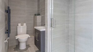 Ein modernes Badezimmer mit Toilette, Waschbecken und Duschbereich.