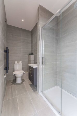 A modern bathroom with a toilet, sink, and shower area. - Modern and Bright Studio in Central Sheffield (Sheffield)