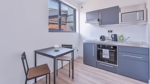 Eine kompakte Küche mit Fenster, einem Tisch und zwei Stühlen sowie modernen Geräten.