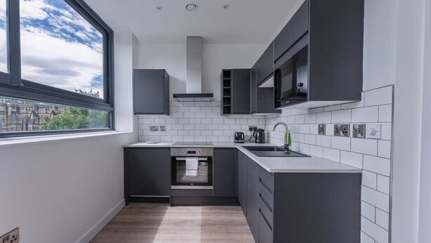 Una cucina moderna con mobili scuri, forno integrato e una finestra che offre vista sulla città.