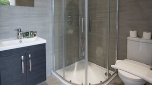 Un bagno moderno con doccia vetrata, un mobile lavabo e un water.