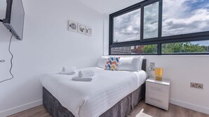 Una camera da letto con un letto, una finestra, un comodino e una TV a parete.
