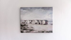 Paesaggio costiero con una fila di edifici bianchi, una spiaggia sabbiosa in primo piano e un cielo nuvoloso.