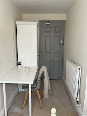 A small, narrow room with a white table, a grey chair, a radiator, and a grey door. - 3 Private Rooms in Shared Apartment with Kitchen (Leeds)