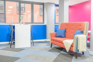 A room with a blue and orange color scheme, a white desk, a blue and orange sofa, and a patterned carpet. - Central Nottingham Cosy Budget Double Studio (Nottingham)