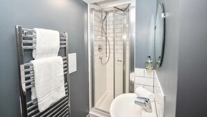 Une salle de bain moderne avec une douche à parois de verre, un lavabo blanc et un porte-serviettes.