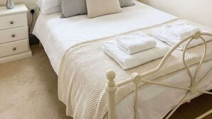 Une chambre à coucher avec un lit, une table de chevet, une lampe et une fenêtre donnant sur des immeubles.
