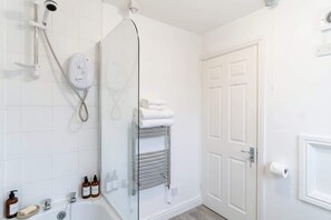 A bathroom with a glass shower enclosure, a white door, and a towel rack with folded towels. - 2 Bedroom Spacious Harbourside Flat with Sea Views (Whitehaven)