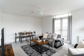 Un salon moderne comprenant un canapé, une table basse, un téléviseur et un coin repas.