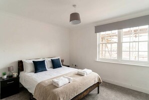 A bedroom with a bed, bedside tables, a window, and a lamp. - 2 Bedroom Spacious Harbourside Flat with Sea Views (Whitehaven)