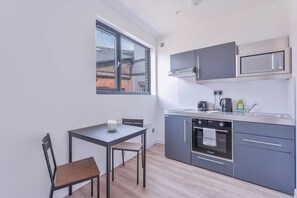 Eine kompakte Küche mit Fenster, einem Tisch und zwei Stühlen sowie modernen Geräten.