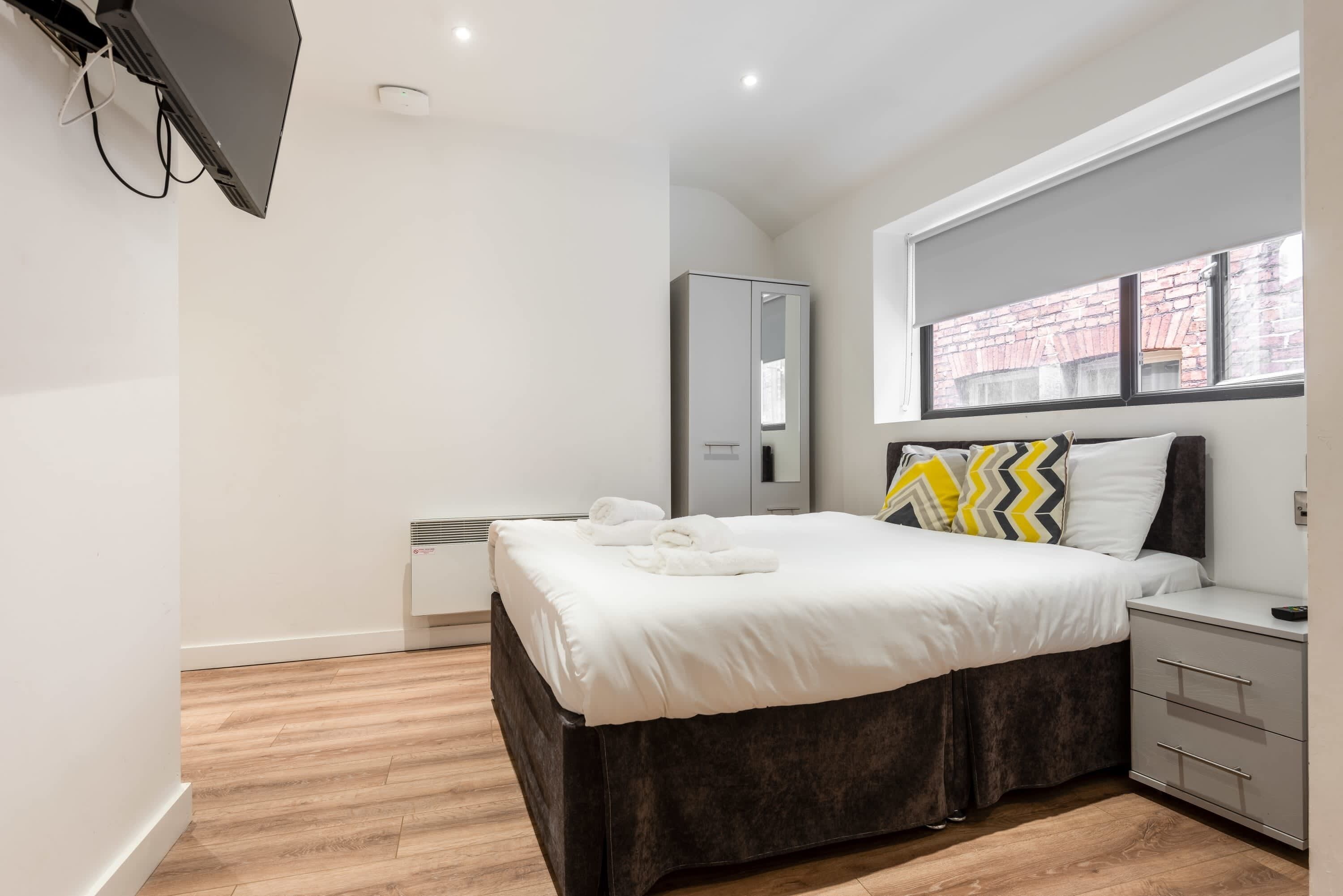 A bedroom with a bed, bedside table, and a window with a view.