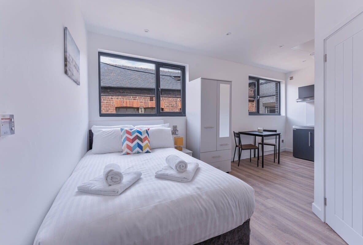 Een moderne hotelkamer met een bed, een bureau en uitzicht op een gebouw van baksteen.