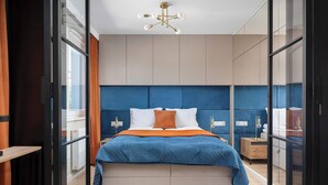 A modern bedroom with a large bed, a bedside table, a nightstand, and a ceiling light fixture. - Family Apartment with Balcony | Air Conditioning, Parking | Tarczyński Arena (Wrocław)