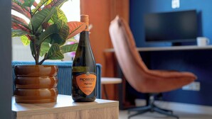 A bottle of Prosecco Treviso wine on a wooden table with a potted plant beside it. - Family Apartment with Balcony | Air Conditioning, Parking | Tarczyński Arena (Wrocław)