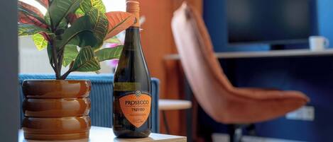 A bottle of Prosecco Treviso wine on a wooden table with a potted plant beside it.