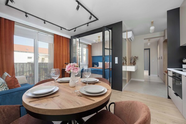 A dining area with a round table, chairs, and a view of the outside.