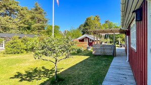 Ett trädäck som leder fram till en röd byggnad med en inglasad veranda.