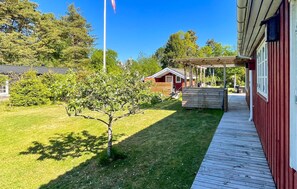 A wooden deck leading to a red building with a covered porch. - Stunning home in Vig with WiFi (Vig)