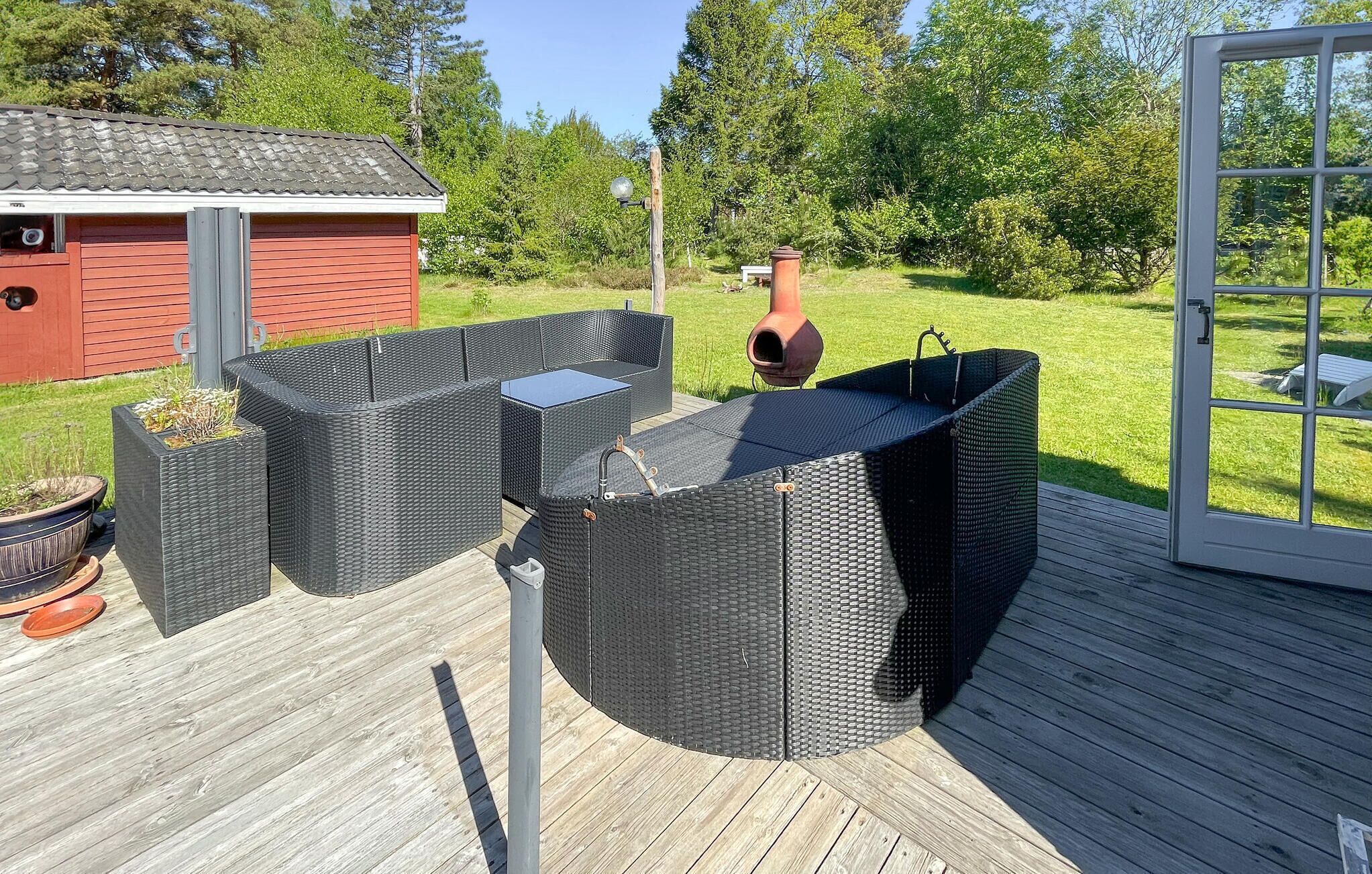 Une terrasse dotée de meubles en osier, d’un abri de jardin rouge et d’une porte en verre.