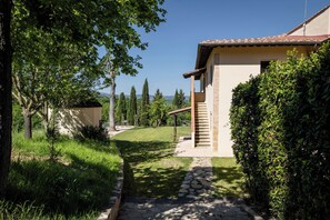 A house with a stone pathway leading to a wooden door, surrounded by greenery and trees. - Villa Tegolato (Barberino Tavarnelle)