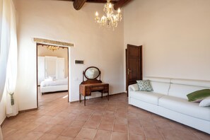 Una habitación con cama, cómoda, espejo, sofá y candelabro.