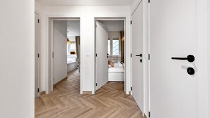 Ein Flur mit Holzboden, weißen Wänden und einem Bett mit Blick auf ein Fenster.