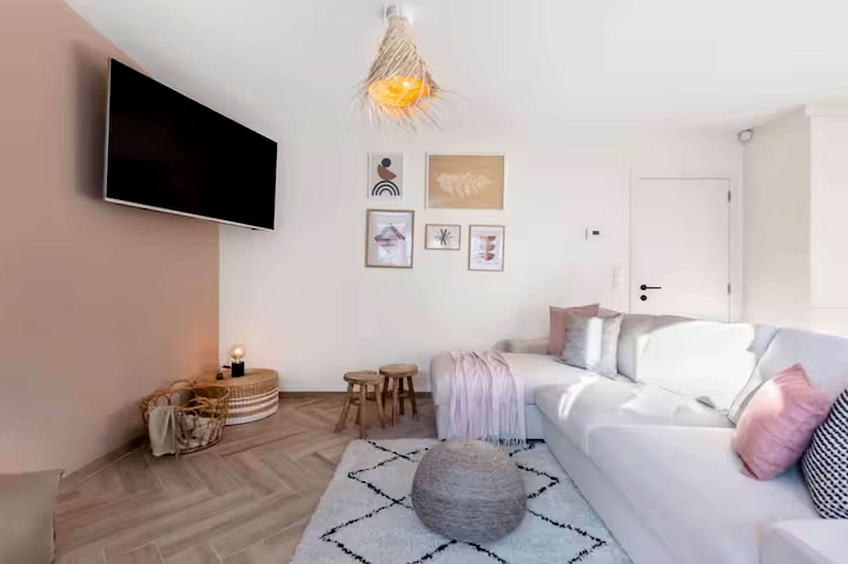 Ett modernt vardagsrum med en platt-TV, en unik hängande lampa och en mysig sittgrupp med en soffa och ett soffbord.