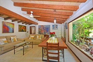 Ein Wohnzimmer mit Holzboden, einem Esstisch mit Stühlen, einer Couch und Bildern an den Wänden.