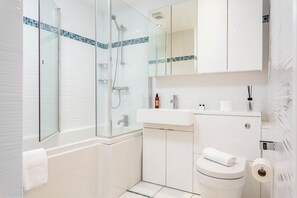 Un baño moderno con ducha envuelta en vidrio, un lavamanos blanco y un inodoro.