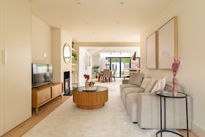A modern living room with a sofa, coffee table, TV, and fireplace. - The Glazed Gable & Alfresco (London)